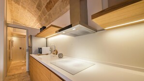 A modern kitchen with a stone ceiling, wooden cabinetry, and a white countertop. - TD Casa Kairos Cozy Smart Apartment in the Center (Polignano a Mare)