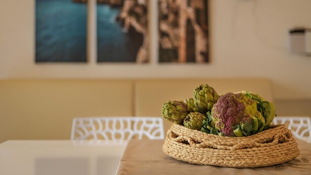 A woven basket on a table with artichokes and a head of cauliflower. - TD Casa Kairos Cozy Smart Apartment in the Center (Polignano a Mare)
