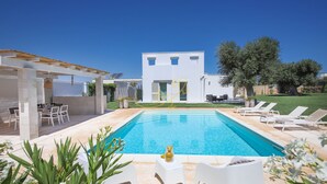 A modern pool area with a clear blue pool, white lounge chairs, and a pergola structure. - TD Villa Patrizia Pool Alfresco Kitchen (Monopoli)