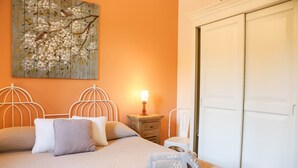 A neatly made bed with pillows and towels, a bedside table with a lamp, and a wall-mounted artwork.