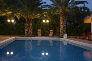 Una piscina con due lettini e un lampione.