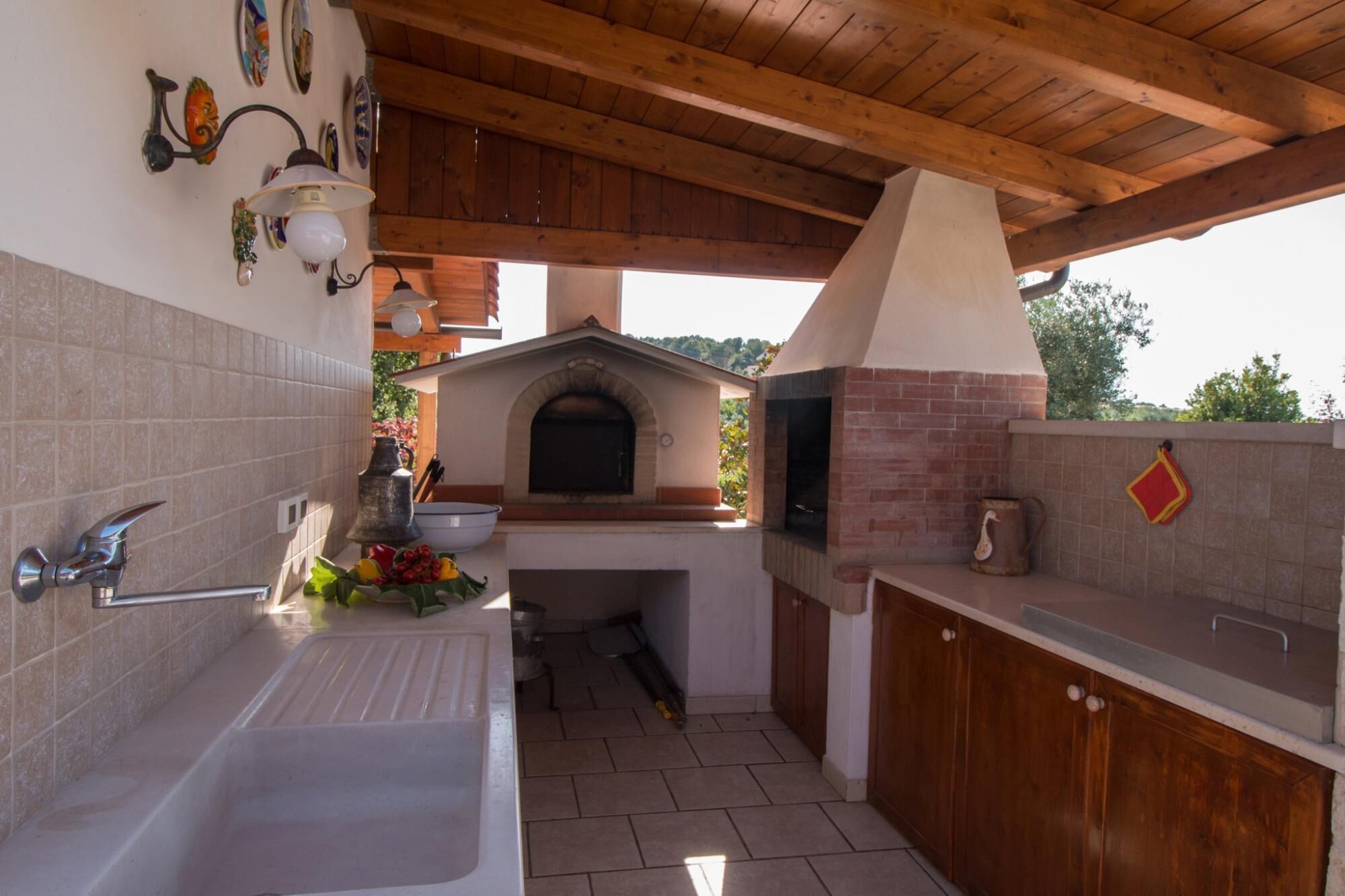 Een keuken met een inbouwoven, een spoelbak en een houten plafond.