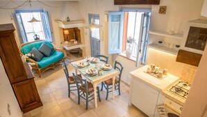 A cozy kitchen with a dining table set for four, a blue sofa, and a view of the outside through a window. - TD Casa Reina in the Historic Center With Terrace (Polignano a Mare)