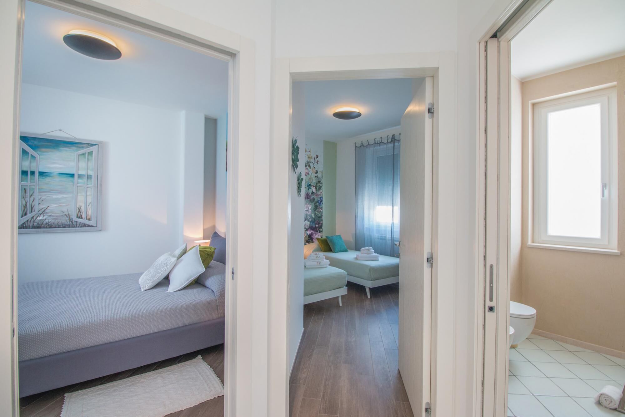 A bedroom with a bed, a painting, and a bathroom with a toilet and a shower.
