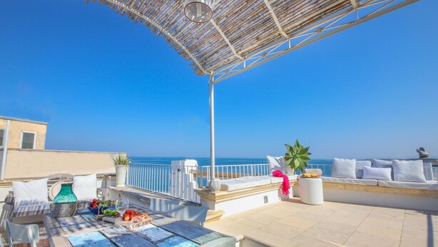 A rooftop terrace with a view of the sea, a table with fruits and a glass, and a white sofa with cushions. - TD Dimora Arcadia With Breathtaking Sea View (Monopoli)