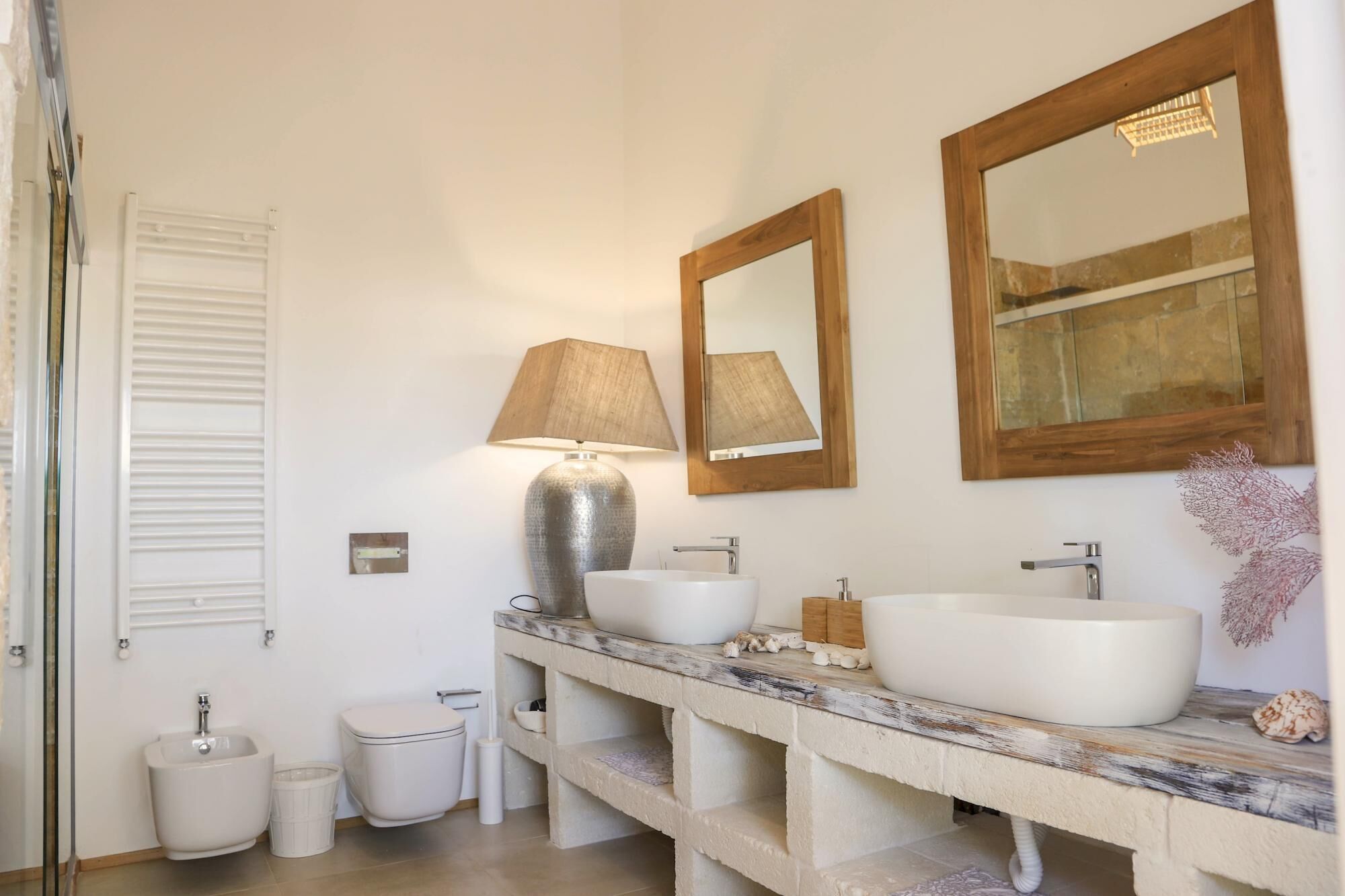 Een badkamer met twee wastafels, een toilet, een bidet en een grote spiegel.