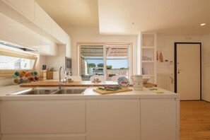A modern kitchen with a central island, a large window, and a view of the outdoors.