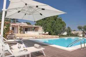 A poolside area with lounge chairs, an umbrella, and a stone building in the background. - TD Villa Fico Jo Villa With Pool Lush Garden (Polignano a Mare)