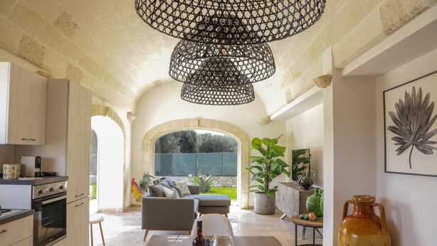 Una cocina amplia con electrodomésticos modernos, un comedor con una mesa dispuesta para dos personas y un gran ventanal con vistas a un jardín.