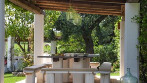 Eine Terrasse im Freien mit einer Holz-Pergola, einem Steintisch und Bänken.