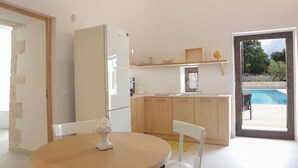 Une cuisine moderne dotée d’un réfrigérateur encastré, de meubles en bois et d’un coin repas avec une table et des chaises.
