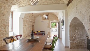 A rustic dining area with a wooden table, chairs, and a stone wall. - TD Trulli Saveni Trulli With Pool Near the Centre (Castellana Grotte)