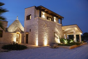 A stone building with a conical roof, a balcony, and a covered outdoor area. - TD Trulli Saveni Trulli With Pool Near the Centre (Castellana Grotte)