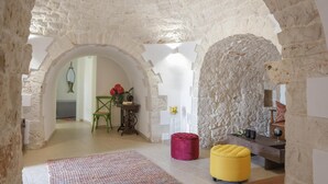 A rustic interior with stone arches, a wooden bench, a yellow ottoman, and a green chair. - TD Trulli Saveni Trulli With Pool Near the Centre (Castellana Grotte)
