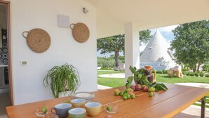 A wooden table with various cups, a potted plant, and fruits. - TD Trulli Saveni Trulli With Pool Near the Centre (Castellana Grotte)