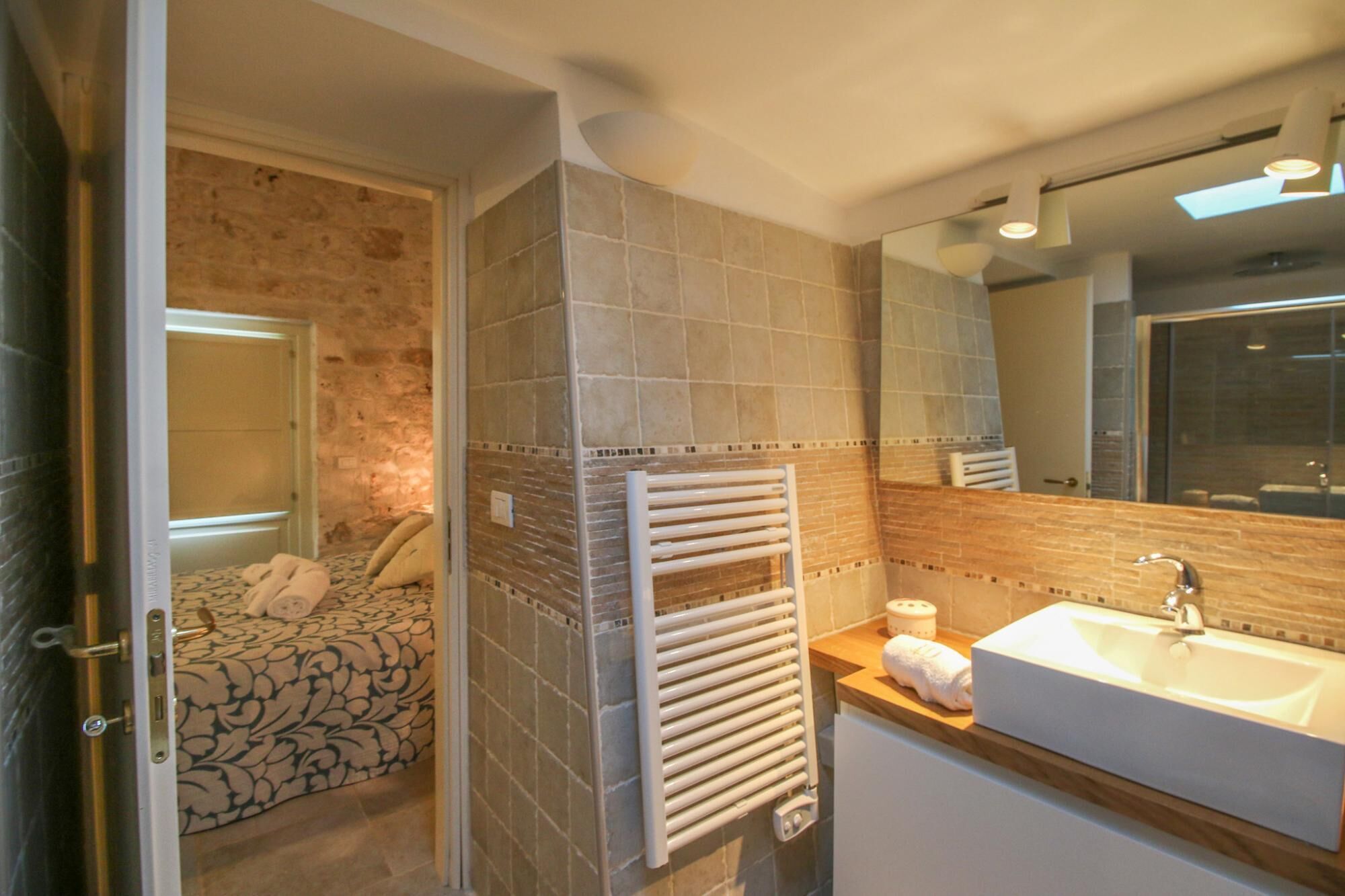 A bathroom with a tiled shower, a white sink, and a towel rack.