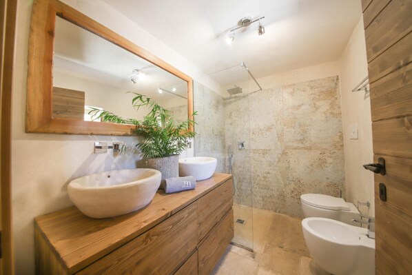 A bathroom with a wooden vanity, two sinks, a large mirror, a potted plant, and a shower area. - TD Trulli di Carole Renovated Trulli With Pool (Ostuni)