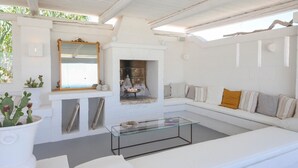 Ein modernes Wohnzimmer mit einem Glastisch, weißen Sofas, einem Kamin und einem großen Spiegel.