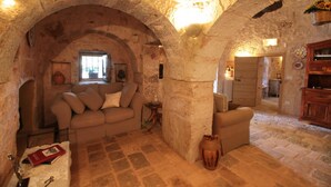 A rustic stone interior with a sofa, a small table, and a vase. - TD Trulli di Montaltino With Stunning Huge Pool (Polignano a Mare)