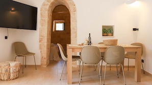 A dining area with a wooden table, woven chairs, and a television mounted on the wall. - TD Trulli Bruco Large Pool for Family Fun (Monopoli)