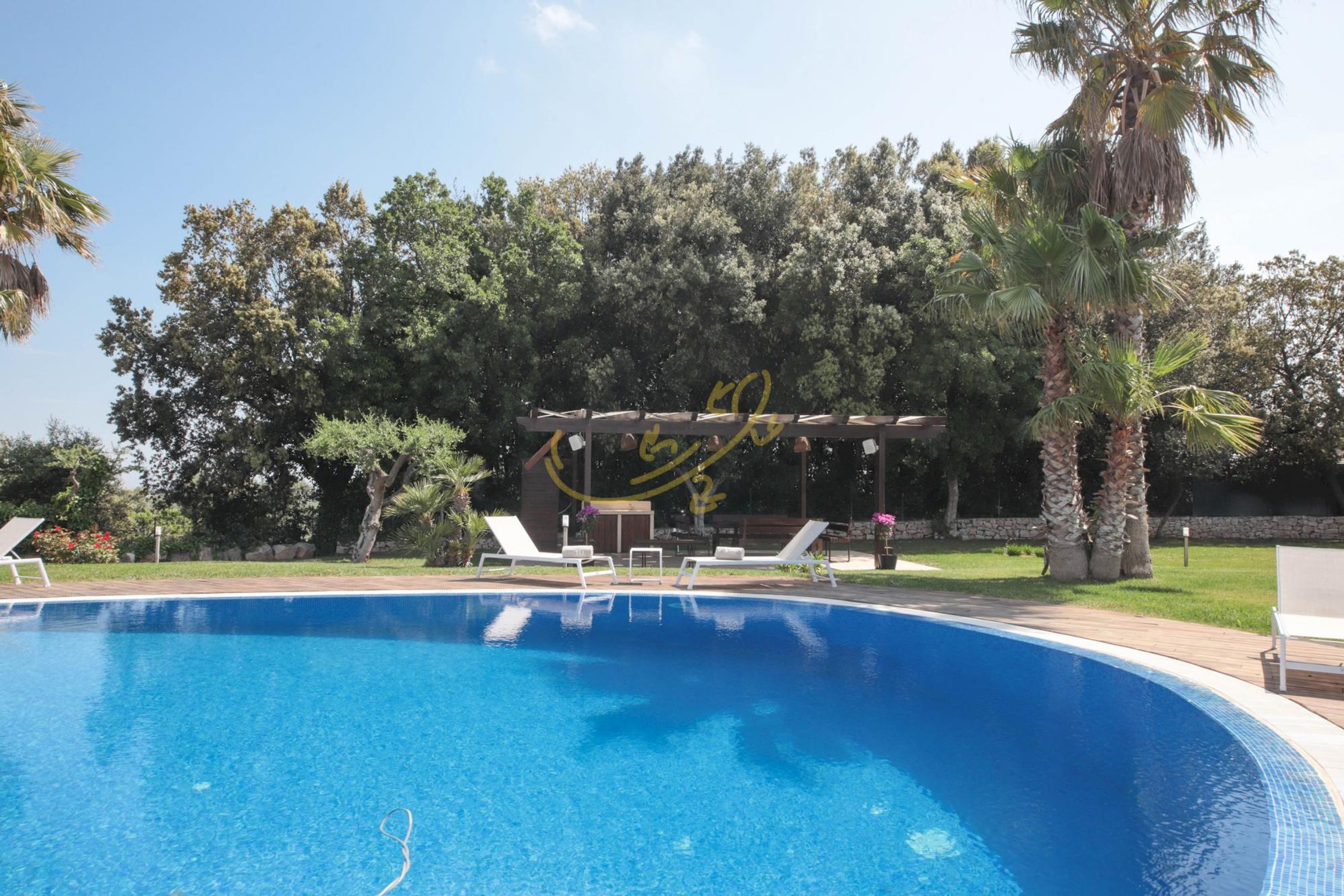Ein Schwimmbecken mit Liegestühlen und einem Pergola mit gelben Graffiti.