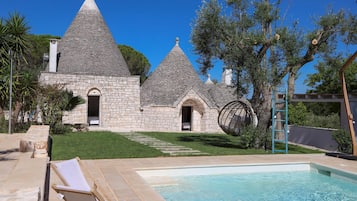 Un bâtiment en pierre doté de toits coniques, d’une piscine et d’un espace extérieur aménagé pour s’asseoir.