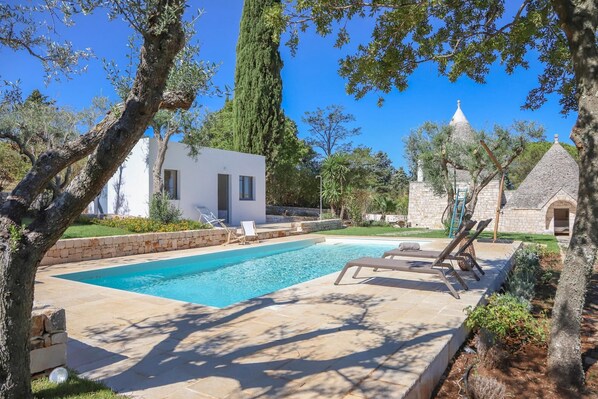 A swimming pool with lounge chairs, a stone building, and a white house with a garden. - TD Trulli Tortorella w Nature Pool Sauna (Monopoli)