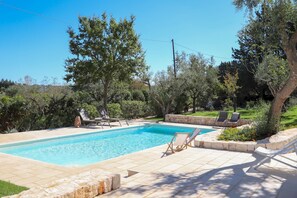 A rectangular swimming pool with a stone border, surrounded by lounge chairs and a stone wall. - TD Trulli Tortorella w Nature Pool Sauna (Monopoli)