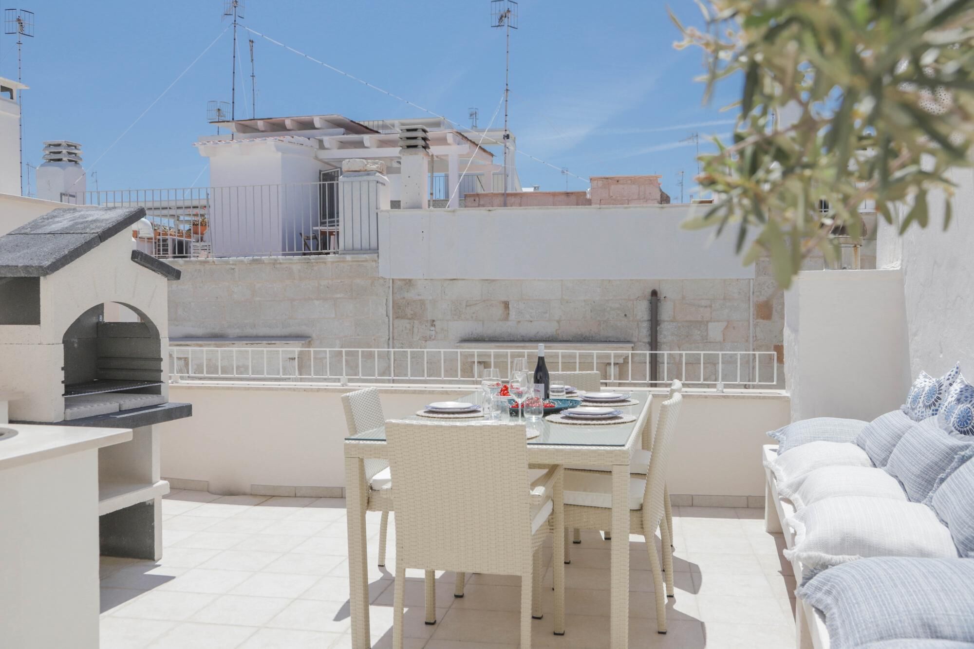 Eine Dachterrasse mit Esstisch für zwei Personen, Grill und einer Sitzecke.