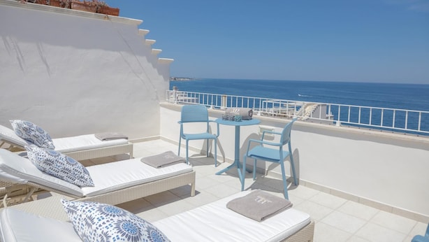 A balcony with white lounge chairs, a small table, and a view of the sea. - TD Casa Marevino Seaside Terrace With Panoramic Views (Polignano a Mare)