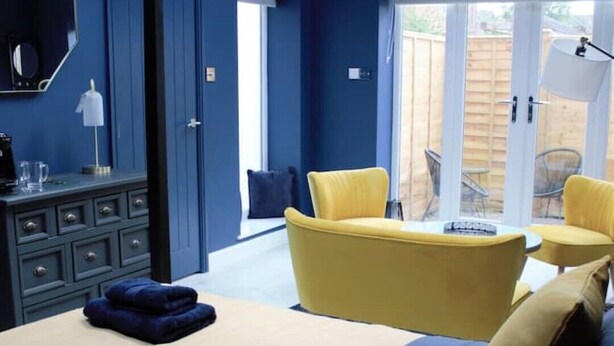 A bedroom with a bed, a dresser, a yellow armchair, and a view of the outside. - Junior suite within walking distance of York city centre (York)