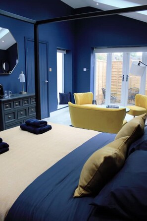 Un dormitorio con cama, cómoda, sillón amarillo y vistas al exterior.