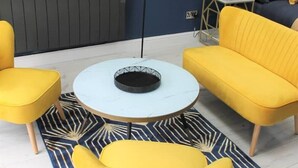 A modern living room with a round coffee table, two yellow armchairs, a sofa, and a floor lamp. - Junior suite within walking distance of York city centre (York)