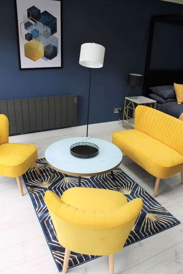 Una sala de estar moderna con una mesita redonda, dos sillones amarillos, un sofá y una lámpara de pie.