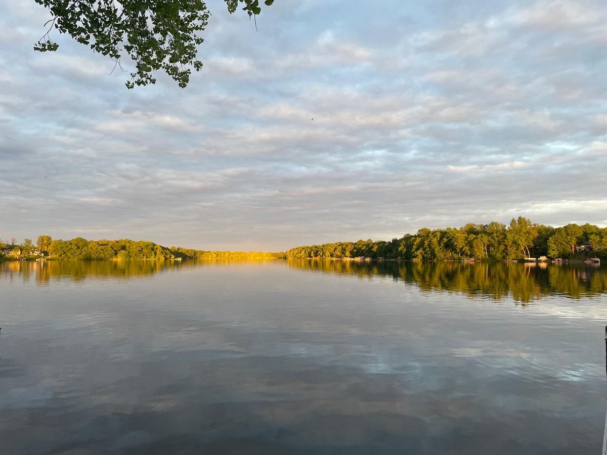 En rolig sø med skovkant og klar himmel.