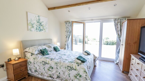 Une chambre à coucher avec un lit, une commode en bois et un téléviseur.