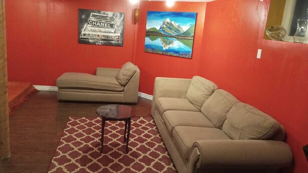 A living room with two sofas, a patterned rug, and two wall-mounted posters. - COZY APARTMENT FOR RENT GREEN NEIGHBORHOOD (Mississauga)