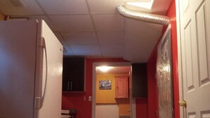 A narrow kitchen with a refrigerator, a microwave, and a sink. There is a door leading to another room. - COZY APARTMENT FOR RENT GREEN NEIGHBORHOOD (Mississauga)