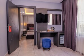 A modern hotel room with a bed, a desk, a television, and a minibar. - Ruby Suit (Istanbul)