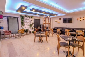 A modern dining area with a central wall featuring a motivational quote, surrounded by tables and chairs. - Ruby Suit (Istanbul)