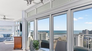 A balcony with a glass table, a potted plant, and a view of the ocean. - Horizon at 77th by Elliott Beach Rentals (Myrtle Beach)