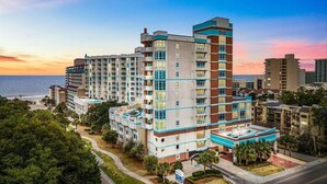 A multi-story hotel with a modern design, featuring balconies and a pool area. - Horizon at 77th by Elliott Beach Rentals (Myrtle Beach)