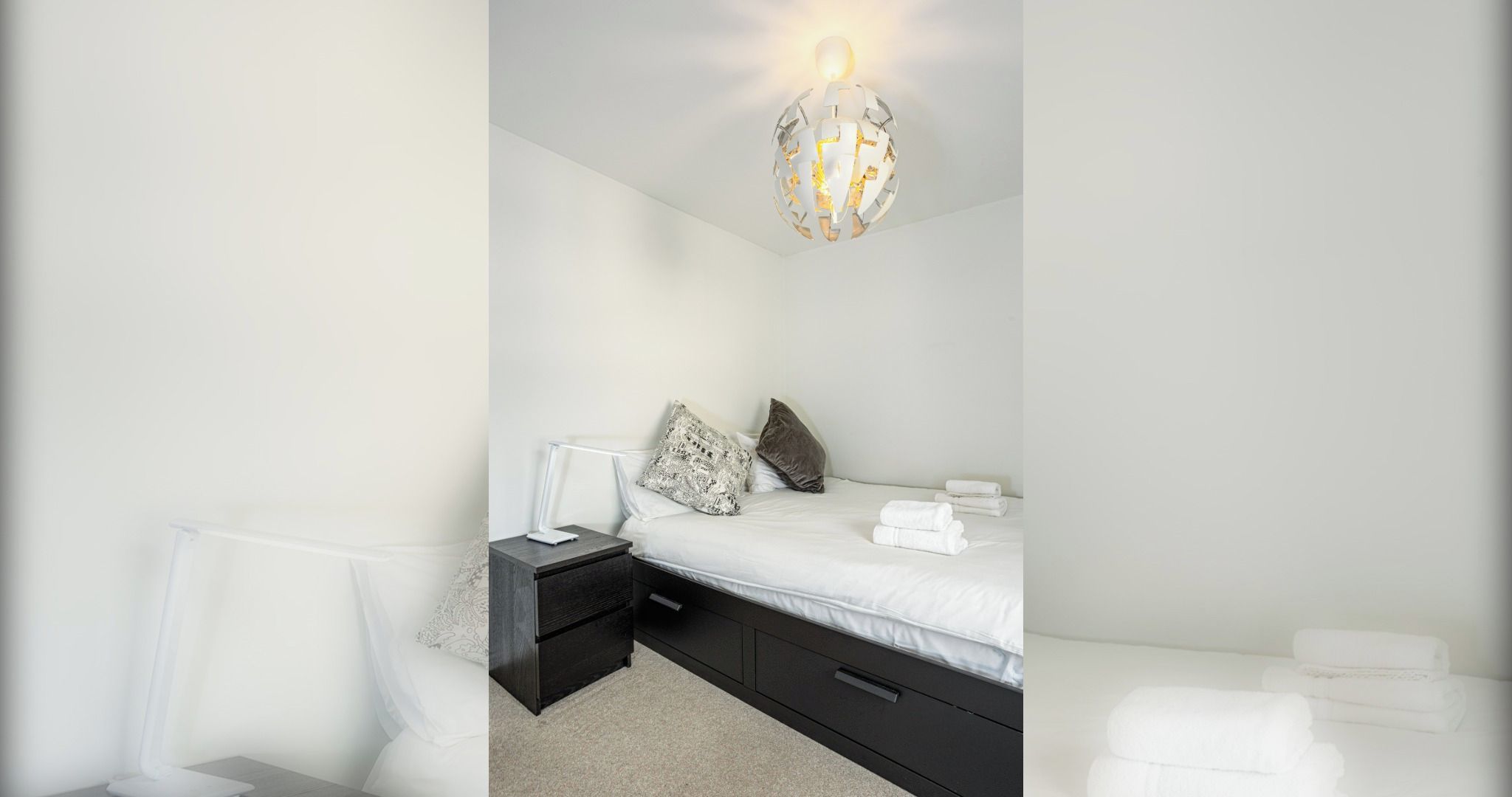 Une chambre à coucher moderne, dotée d’un lit, de tables de chevet et d’un luminaire sphérique original.