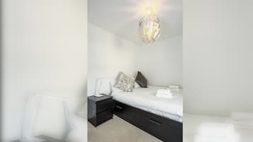 Une chambre à coucher moderne, dotée d’un lit, de tables de chevet et d’un luminaire sphérique original.