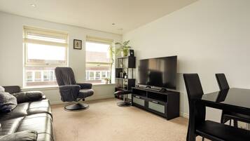 A modern living room with a sofa, a chair, a TV, and a bookshelf.