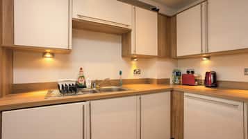 Une cuisine moderne avec des meubles blancs, un évier en acier inoxydable et un plan de travail en bois.