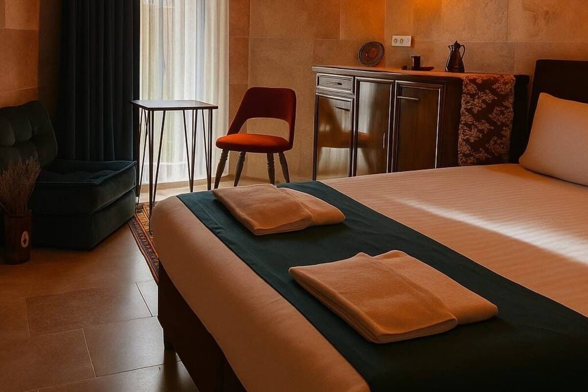 A hotel room with a bed, a desk, a chair, and a window with curtains.