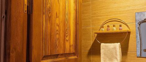 A wooden door in a bathroom with a tiled wall, a sink, and a towel hanging on a rack.
