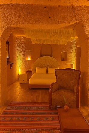 A bedroom with a bed, a chair, a nightstand, and a lamp. - Grand Uçhisar Hotel (Nevsehir)