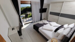 A hotel room with a bed, a desk, a chair, a TV, and a balcony with a view. - Apartment, 4BDR, shared pool (Sarajevo)